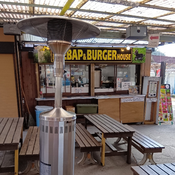 BEYZADE KEBAP HOUSE様でのヒーター利用例写真。店舗前の簡易屋根で覆われた屋外ベンチ席の近くにヒーターが設置されている。
