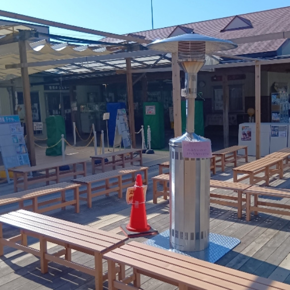 愛知牧場モーハウス売店様でのヒーター利用例写真。屋外に設置されたベンチ付近にヒーターが設置されている。