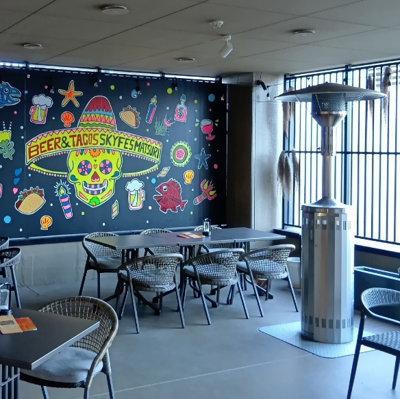 Sky fes様でのパラソルヒーター利用例写真。屋根やパネルはあるものの壁のない半屋外風の店内にヒーターが設置されている。
